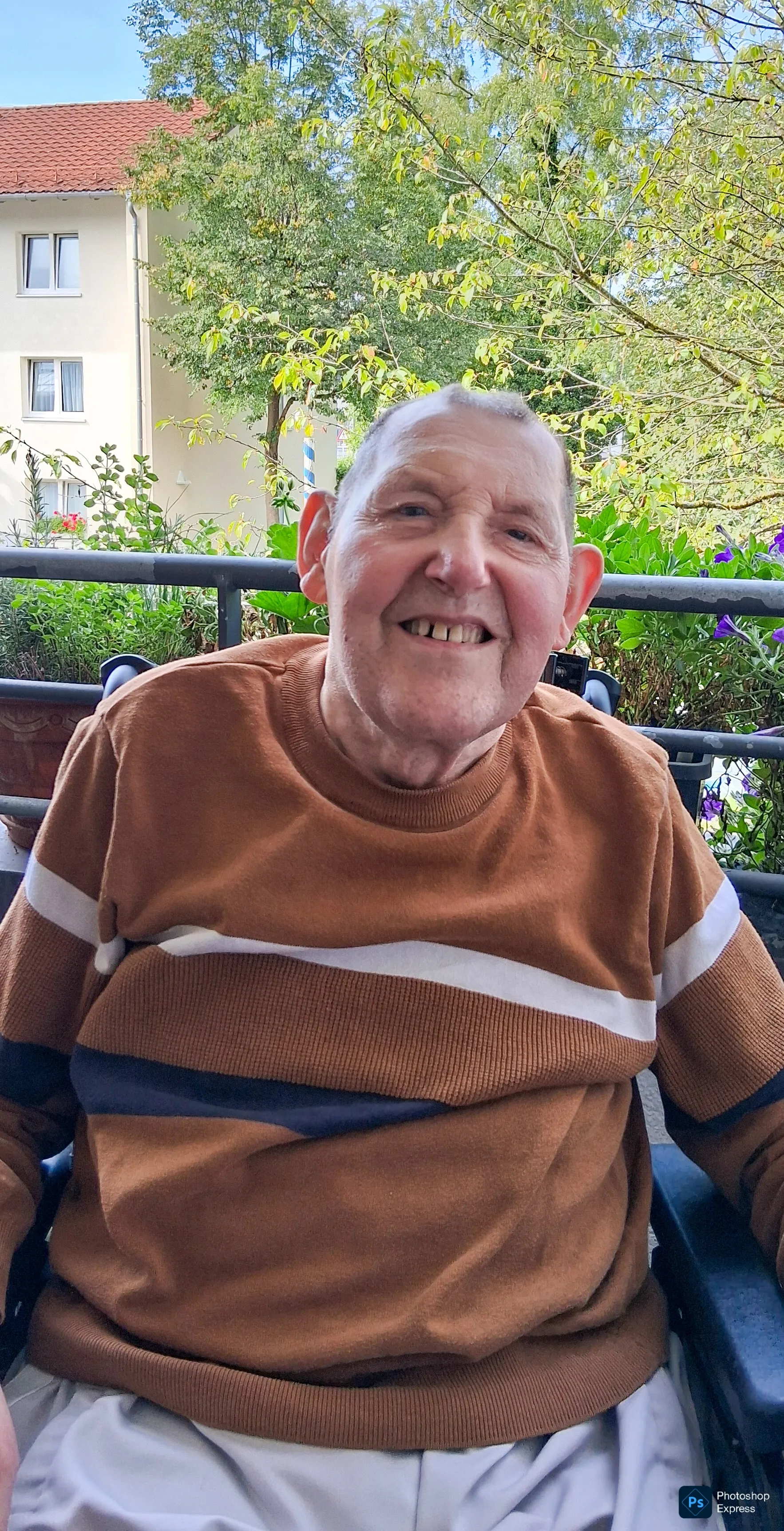 Anton Peter sitzt in seinem Rollstuhl auf dem Balkon und l&auml;chelt