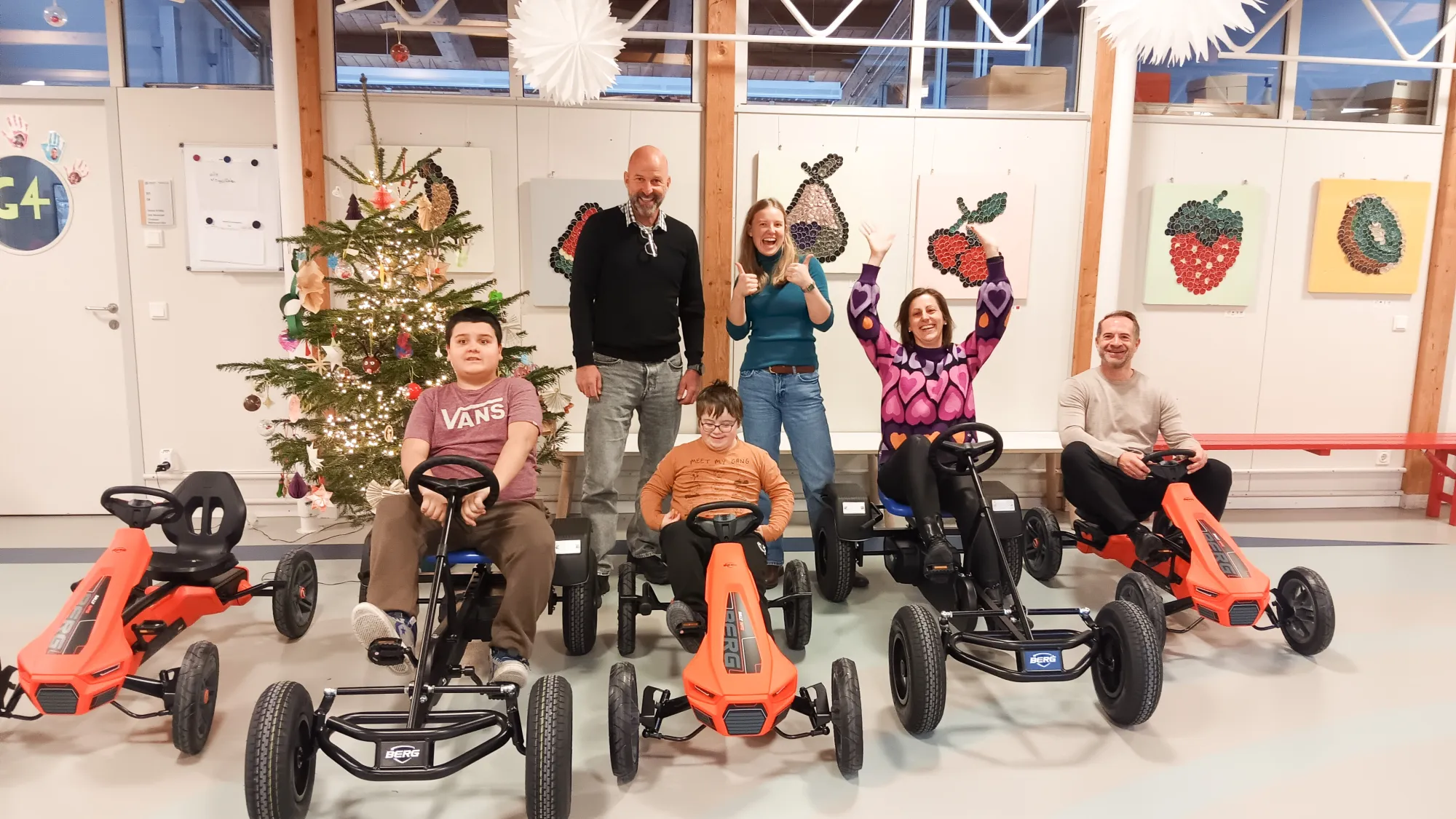 Fünf Gokarts, auf denen Kinder und Erwachsene sitzen. Foto von der Spendenübergabe.