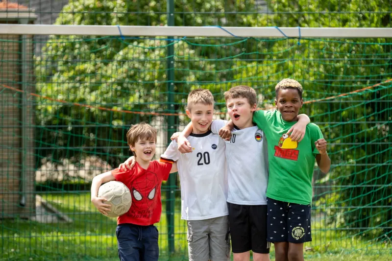 Drei Jungen mit Fu&szlig;ball auf dem Sportplatz